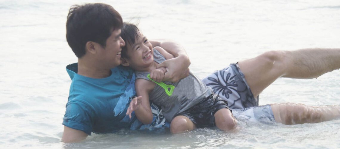 father and son smiling in the ocean
